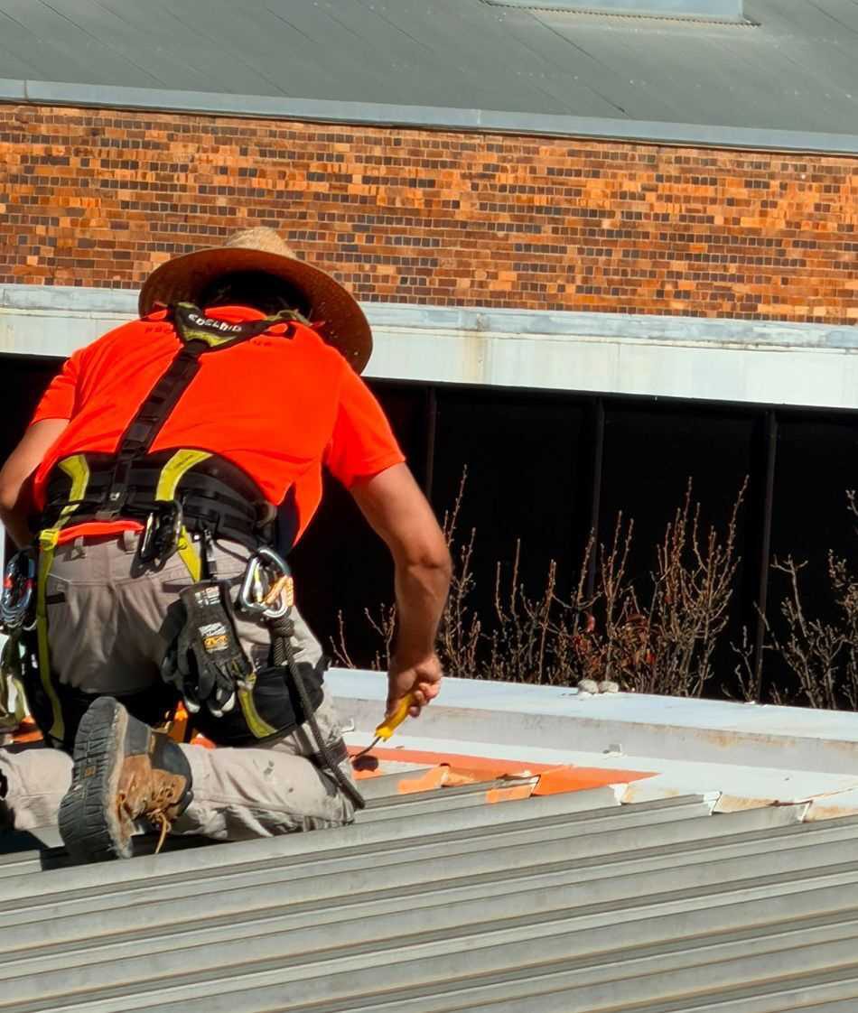 A Deca technician in full harness applying primer on the roof